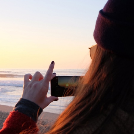 Girl taking a photograph at sunset