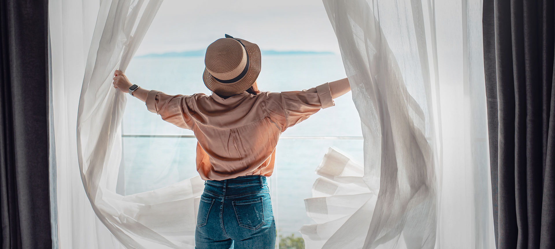 Turista abriendo las cortinas de su alojamiento Turista abriendo las cortinas de su alojamiento